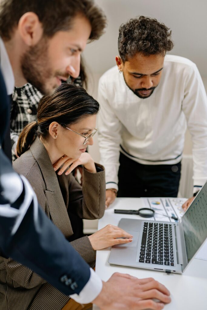 A diverse group of professionals collaborating on a laptop in an office setting.
